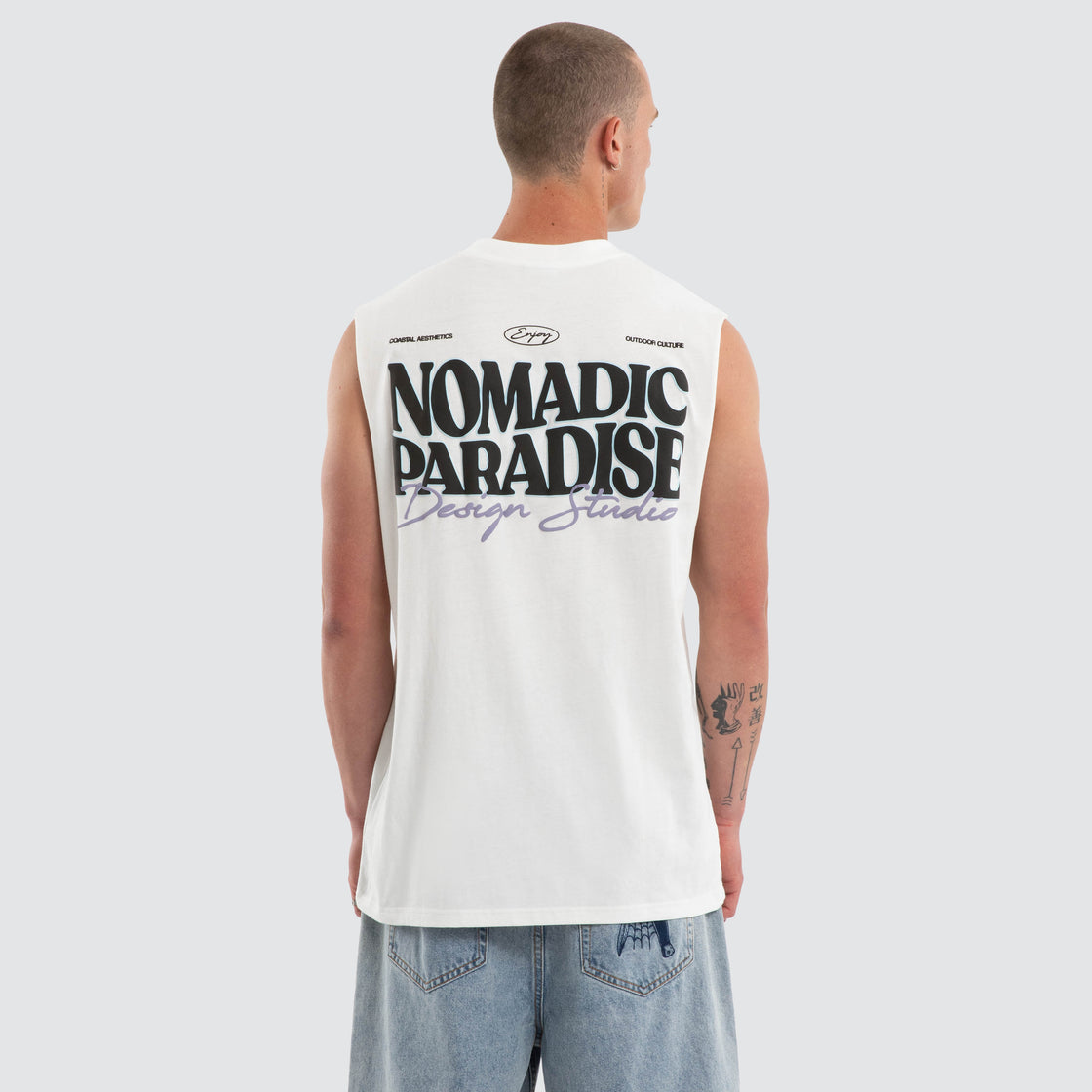 Person wearing a sleeveless shirt with 'Nomadic Paradise' text on the back, standing against a plain background.